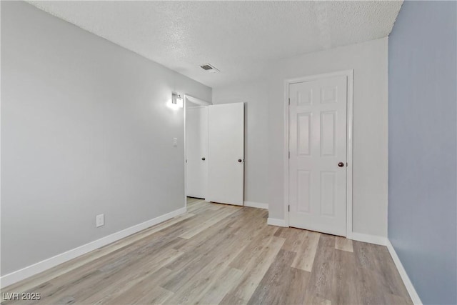 unfurnished bedroom with visible vents, baseboards, a textured ceiling, and light wood-style flooring