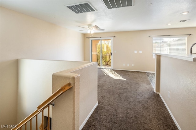 hallway featuring dark colored carpet and a healthy amount of sunlight