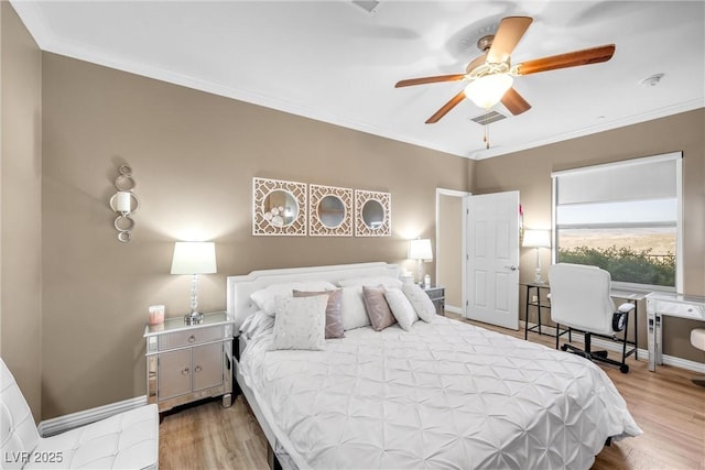 bedroom featuring visible vents, ornamental molding, a ceiling fan, wood finished floors, and baseboards