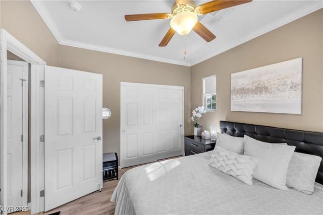 bedroom featuring crown molding, light wood-style floors, a closet, and ceiling fan