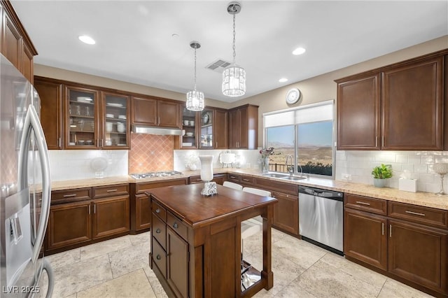kitchen with visible vents, a sink, under cabinet range hood, backsplash, and appliances with stainless steel finishes