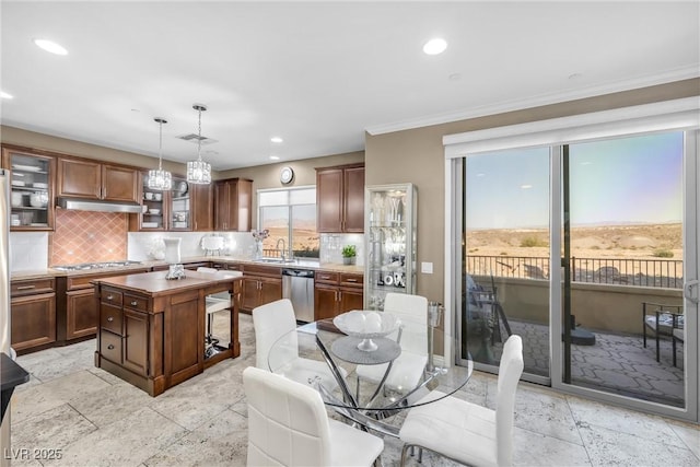 kitchen with appliances with stainless steel finishes, backsplash, a center island, hanging light fixtures, and sink