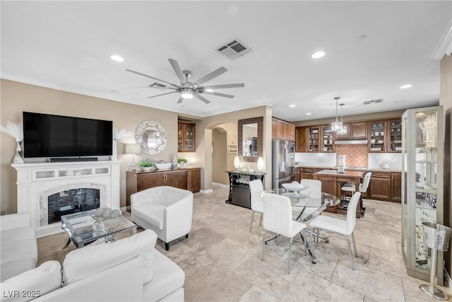 living area featuring recessed lighting, arched walkways, visible vents, and a high end fireplace