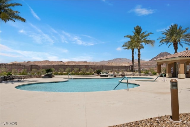 pool featuring a patio area, a mountain view, and fence