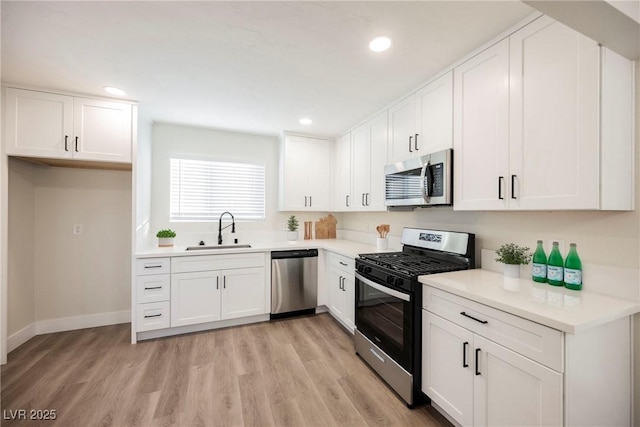 kitchen with white cabinetry, sink, light hardwood / wood-style floors, and appliances with stainless steel finishes