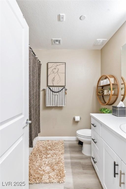 bathroom featuring vanity, toilet, wood-type flooring, and a textured ceiling