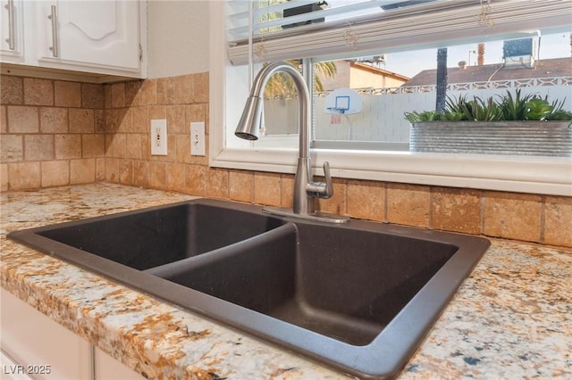 room details with white cabinets, decorative backsplash, and sink