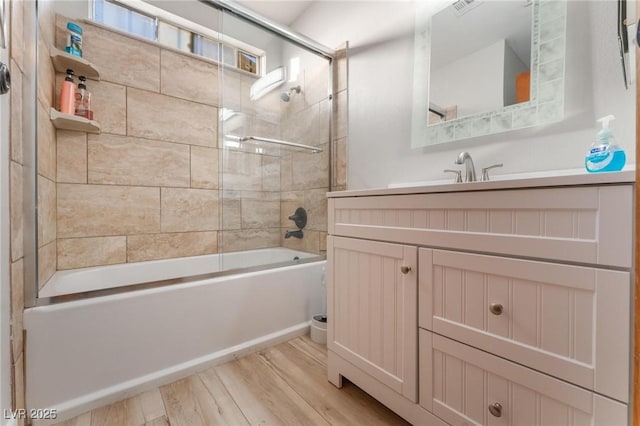 bathroom featuring hardwood / wood-style floors, vanity, and combined bath / shower with glass door