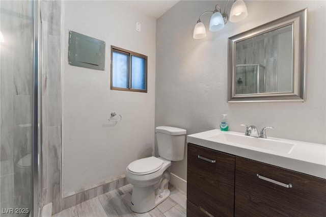 bathroom featuring a shower with door, vanity, and toilet