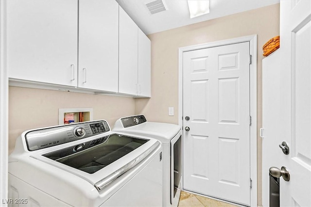 laundry area featuring cabinets, light tile patterned floors, and washing machine and dryer