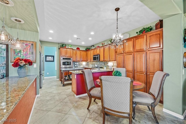 kitchen featuring backsplash, light stone counters, pendant lighting, and stainless steel appliances