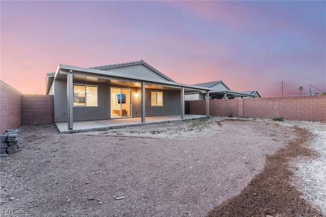 back house at dusk featuring a patio