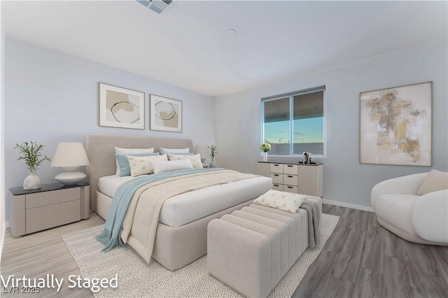 bedroom with visible vents, baseboards, and wood finished floors