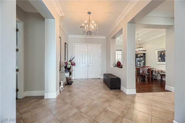 tiled entryway with ornamental molding and an inviting chandelier