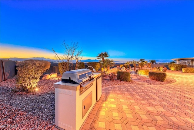 patio terrace at dusk with a grill and exterior kitchen