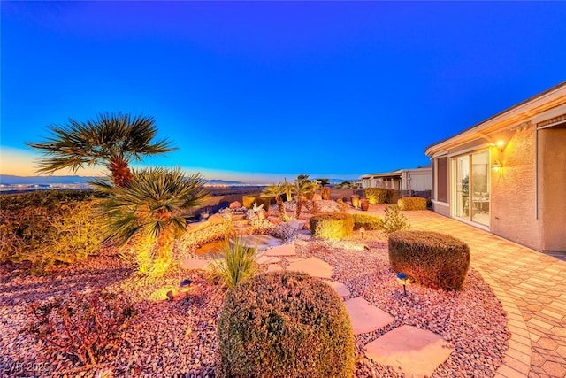 yard at dusk featuring a patio