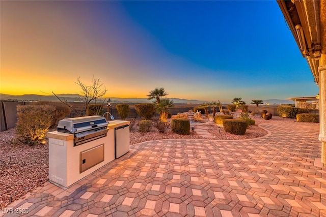 patio terrace at dusk featuring a grill and area for grilling