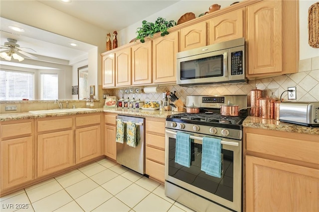 kitchen with light brown cabinetry, backsplash, stainless steel appliances, and sink