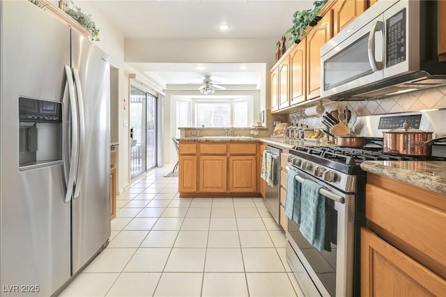 kitchen with ceiling fan, light stone counters, backsplash, light tile patterned flooring, and appliances with stainless steel finishes