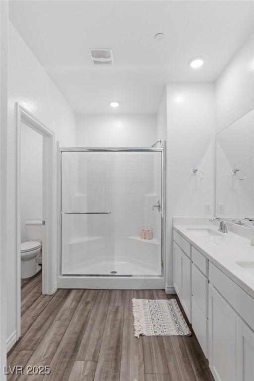 bathroom featuring vanity, wood-type flooring, an enclosed shower, and toilet