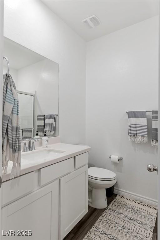 bathroom featuring toilet, vanity, wood-type flooring, and walk in shower