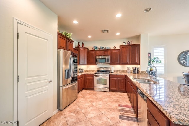 kitchen with sink, light stone counters, light tile patterned floors, appliances with stainless steel finishes, and kitchen peninsula