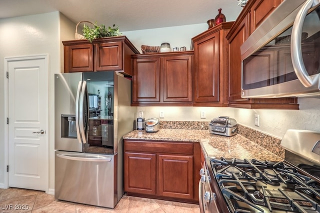 kitchen featuring stainless steel appliances, light stone countertops, and light tile patterned floors