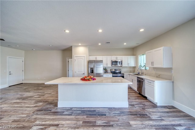 kitchen featuring white cabinetry, sink, dark wood-type flooring, stainless steel appliances, and a kitchen island