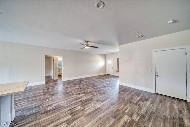 unfurnished living room with ceiling fan, dark wood-type flooring, and a textured ceiling