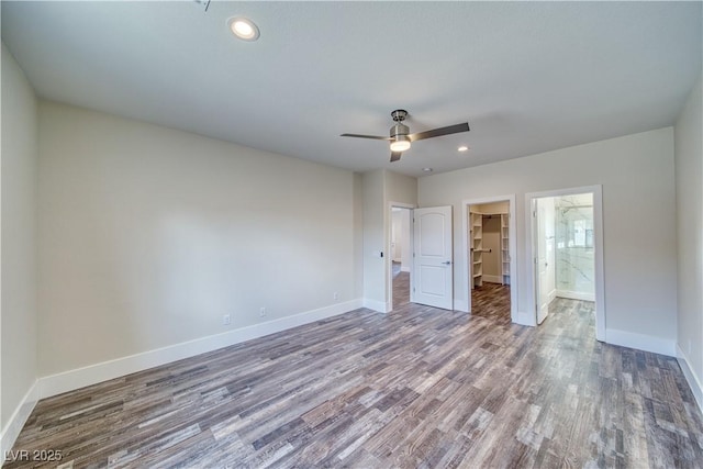 unfurnished bedroom featuring hardwood / wood-style floors, a walk in closet, a closet, and ceiling fan