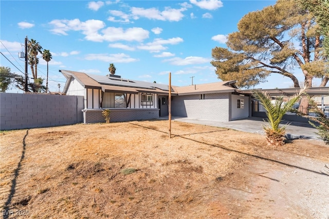 ranch-style home with a patio area and solar panels