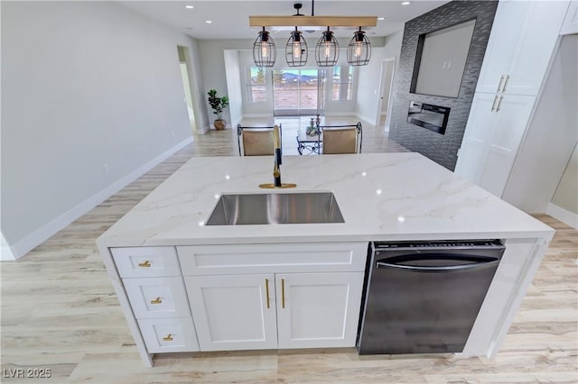 kitchen with light stone countertops, a large fireplace, white cabinetry, and sink