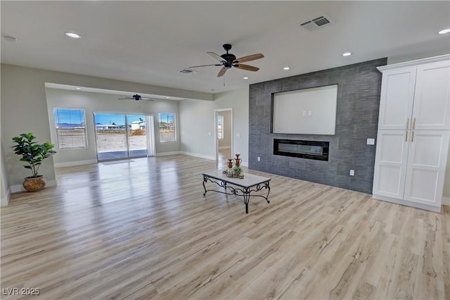 living room featuring ceiling fan, light hardwood / wood-style floors, and a fireplace