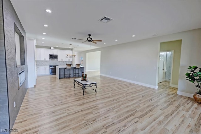 living room with ceiling fan and light hardwood / wood-style flooring