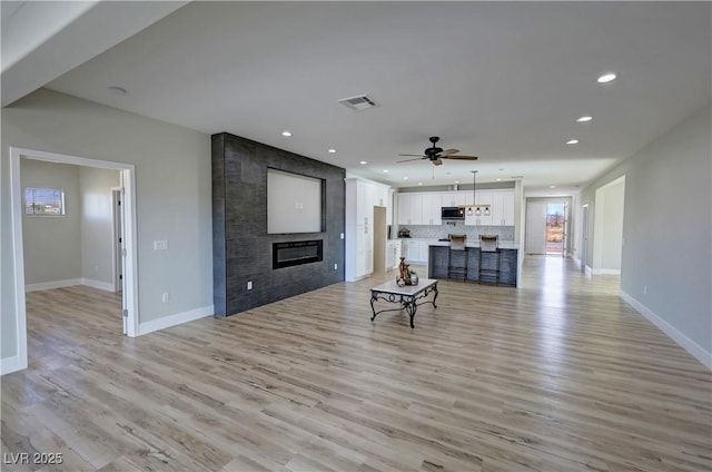 living room with a fireplace, light hardwood / wood-style flooring, and ceiling fan