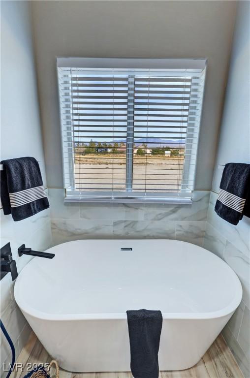 bathroom featuring a bathtub, hardwood / wood-style floors, and tile walls