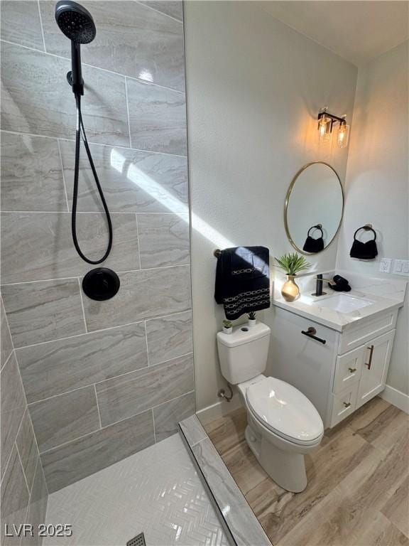 bathroom featuring tiled shower, toilet, vanity, and hardwood / wood-style flooring