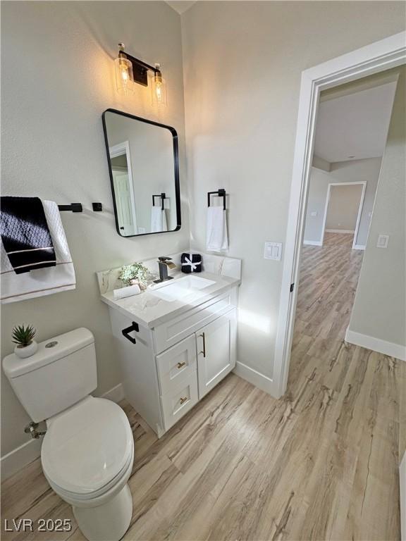 bathroom with hardwood / wood-style floors, vanity, and toilet