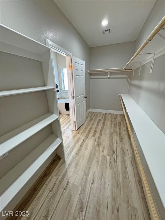 walk in closet with hardwood / wood-style flooring