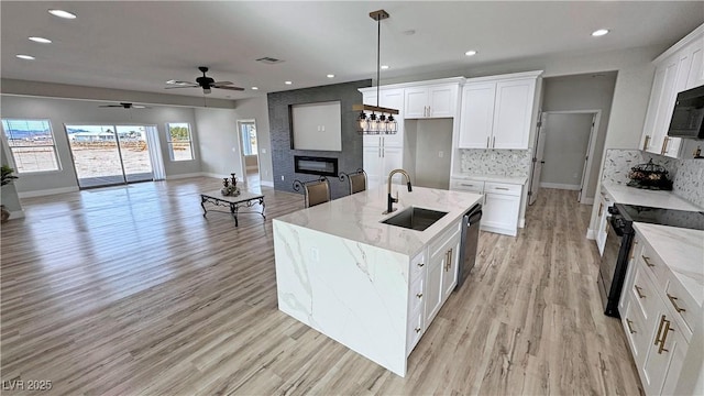 kitchen with decorative backsplash, white cabinetry, sink, and an island with sink