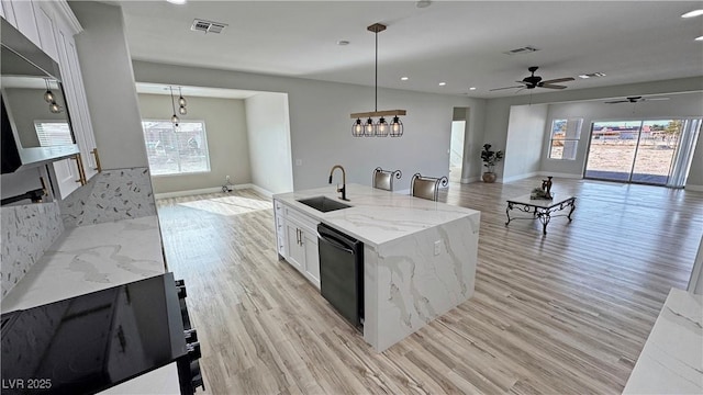 kitchen with white cabinetry, dishwasher, sink, hanging light fixtures, and an island with sink