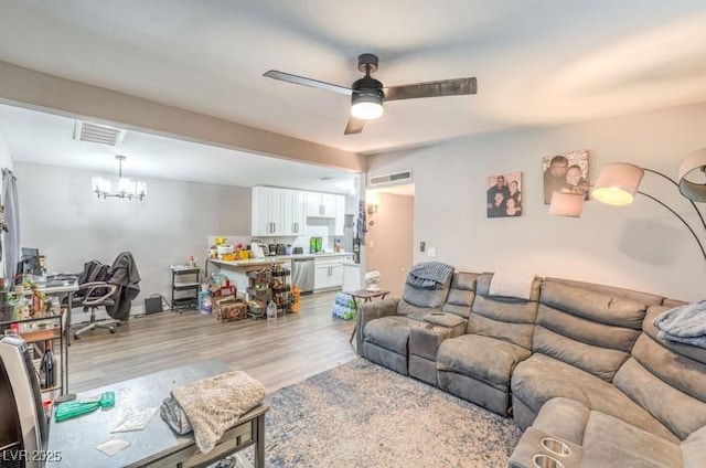 living room featuring ceiling fan with notable chandelier and light wood-type flooring