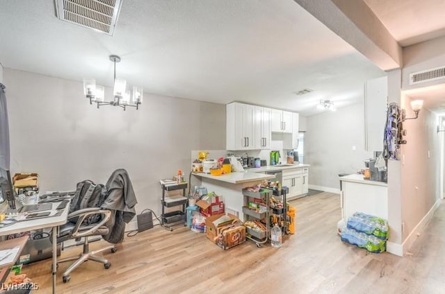 interior space featuring kitchen peninsula, light hardwood / wood-style flooring, a notable chandelier, white cabinets, and hanging light fixtures