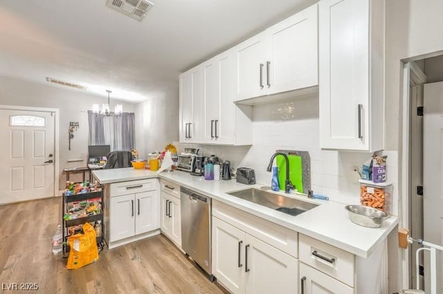 kitchen with dishwasher, white cabinets, sink, hanging light fixtures, and kitchen peninsula