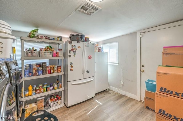 kitchen with separate washer and dryer, light hardwood / wood-style flooring, white fridge, and a textured ceiling