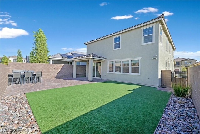 back of property with a yard and a patio area