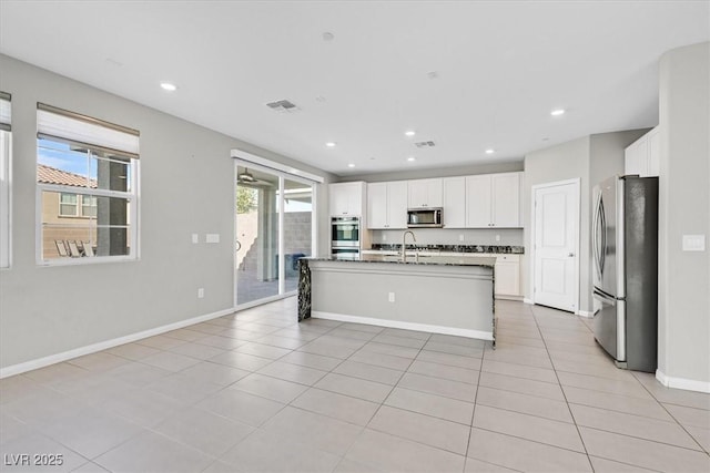 kitchen featuring white cabinetry, sink, stainless steel appliances, a kitchen island with sink, and light tile patterned floors