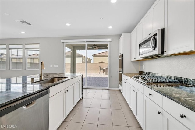 kitchen featuring appliances with stainless steel finishes, white cabinetry, plenty of natural light, and sink