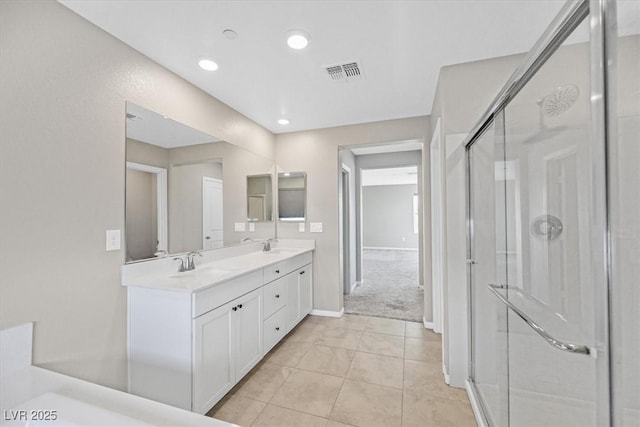 bathroom with a shower with door, vanity, and tile patterned flooring