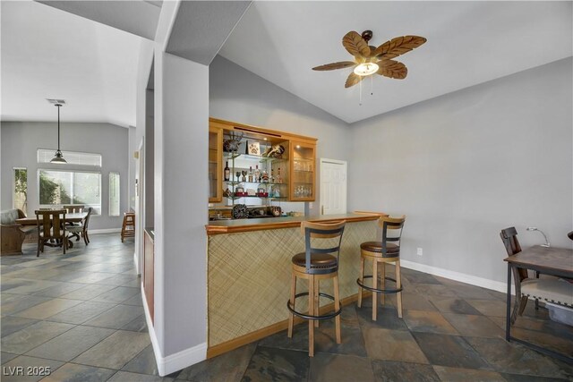 bar with decorative light fixtures, vaulted ceiling, and ceiling fan